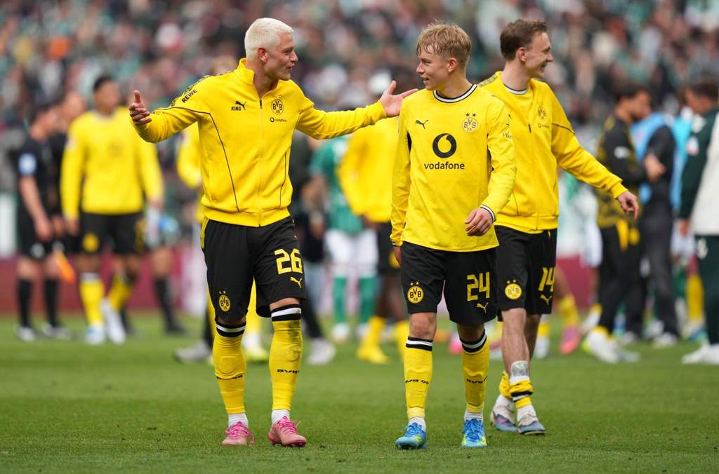 Pemain Borussia Dortmund Julian Ryerson dan Waldemar Anton merayakan kemenangan di lapangan hijau setelah pertandingan Bundesliga berakhir.